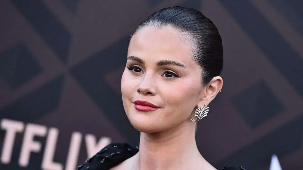 Head and shoulders image of Selena Gomez in sparkly black top and leaf shaped earring as she poses for pictures during a premiere of Marty, Life is Short in May 2026.