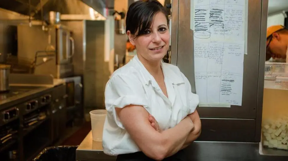 Amanda Cohen stands in her restaurant kitchen with her arms crossed
