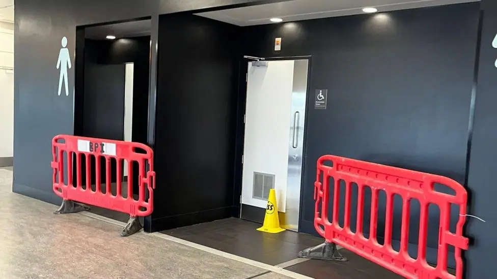 A toilet exterior with plastic barriers in front of the doors.