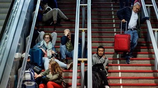 Passengers looking stressed while sitting on the steps of Atocha train station during April's power cut.