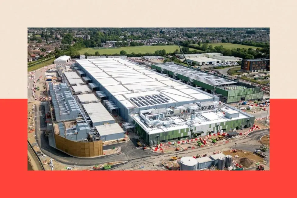 A large white data centre building under construction in Hertfordshire, surrounded by green land, a river and housing estates further afield.