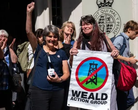 Sarah Finch raises a fist in the air outside the supreme court in London next to another woman holding a Weald Action Group sign