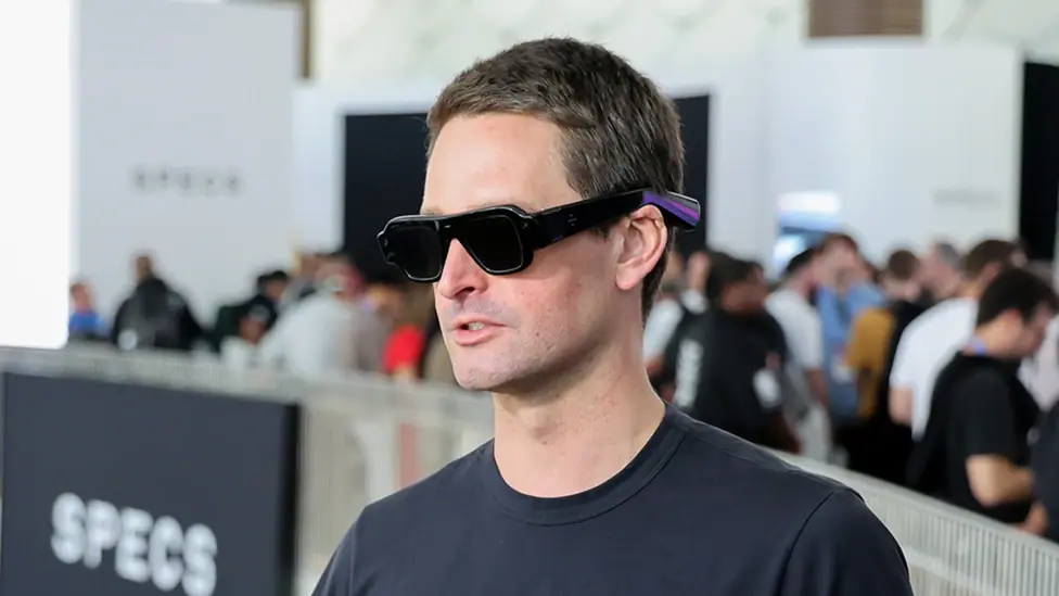 Evan Spiegel, a man with short hair, wears the glasses. They are a bit like goggles mixed with large aviator sunglasses.