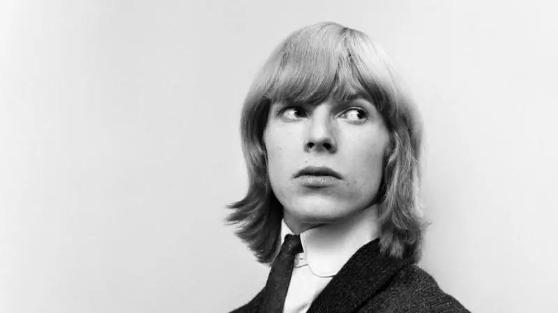Black and white photo of a man with shoulder length light coloured hair - a stylised studio shot with no background