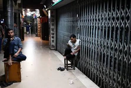 Two men sit outside closed shops