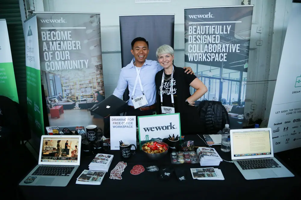 People working at the WeWork exhibit table at TechCrunch Disrupt NYC 2017