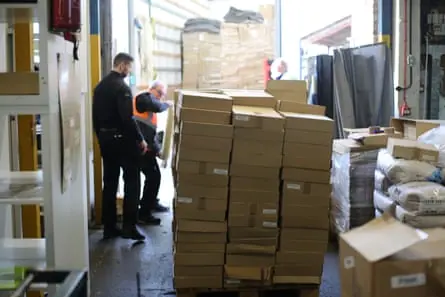 Police officers inspect piles of counterfeit vinyl in a warehouse.