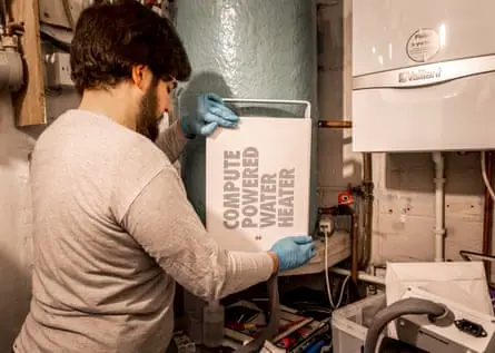 A man wearing gloves holds a heata unit he is about to install in a home