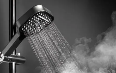 A shower head with running water and soothing steam in a bathroom.