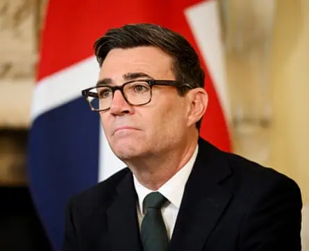Andy Burnham in a suit and tie in front of the union flag