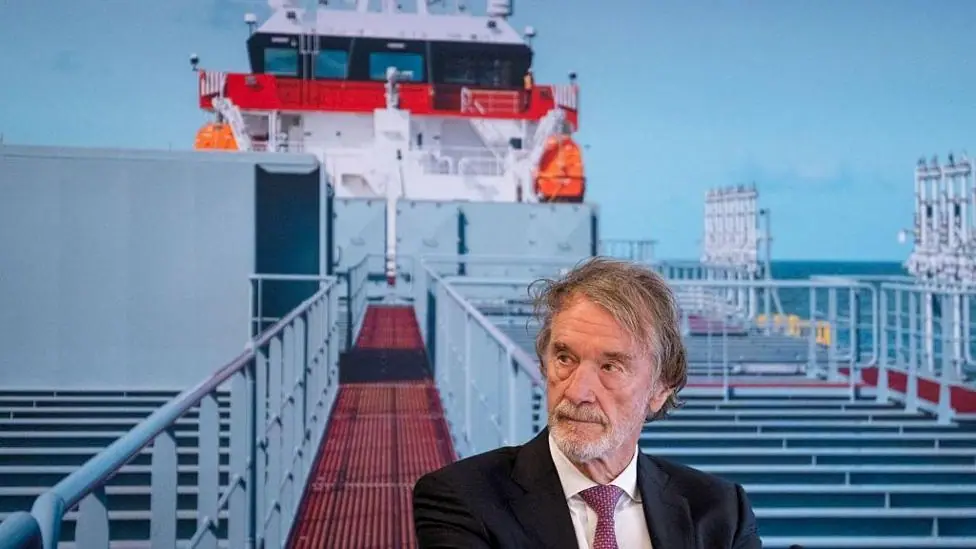 Head and shoulders of a bearded man in suit and tie standing on a ship's gangplank or walkway
