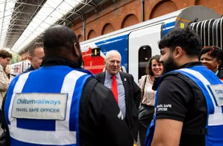 Lord Hendy smiles as he speaks with Chiltern Railways staff as they stand next to a train carriage