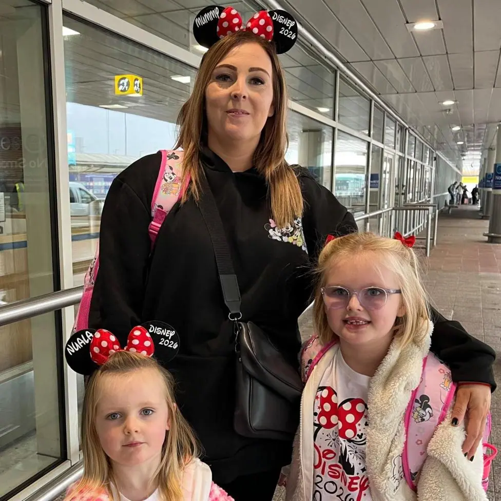 A woman and two girls, wearing minnie mouse ears.