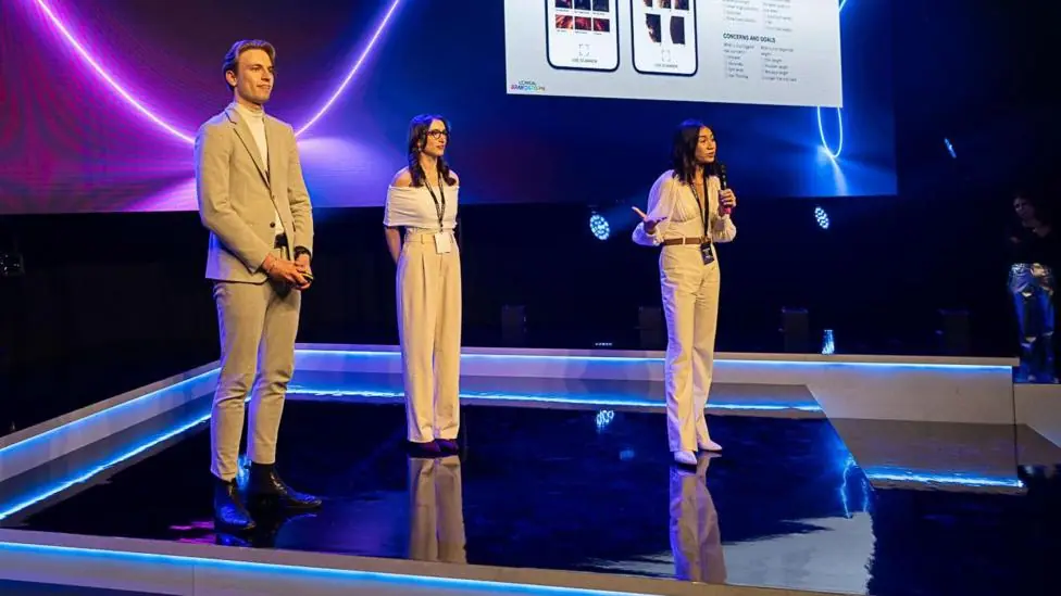 Yumi Liberman, centre, and her two friends up on stage at the UK final of L'Oreal's Brandstorm competition