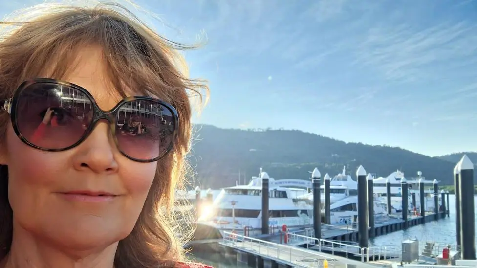 Karen Green wearing sunglasses as she stands in front of a harbour full of boats