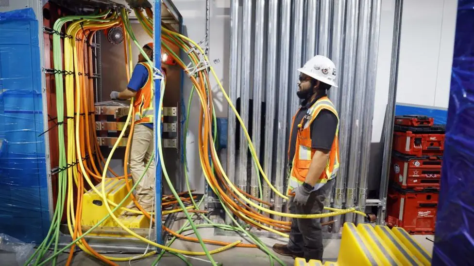 Two workers in hi-vis jackets work with bundles of cabling at a data centre project