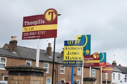 A row of estate agents’ signs in front of a row of terrace houses