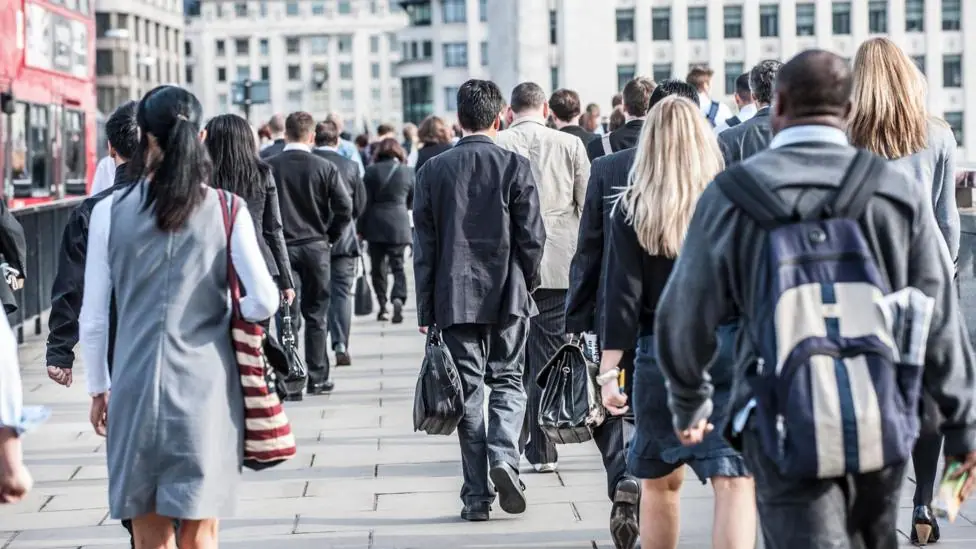 Commuters walking along a pavement in a city