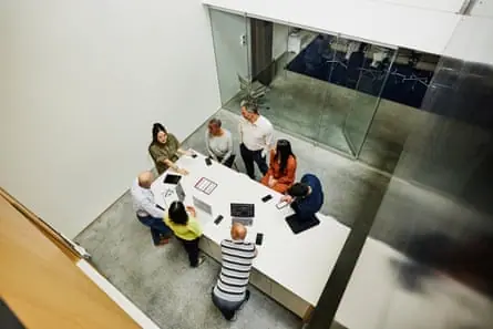 Wide, high-angle shot of a businesswoman leading a project meeting in office
