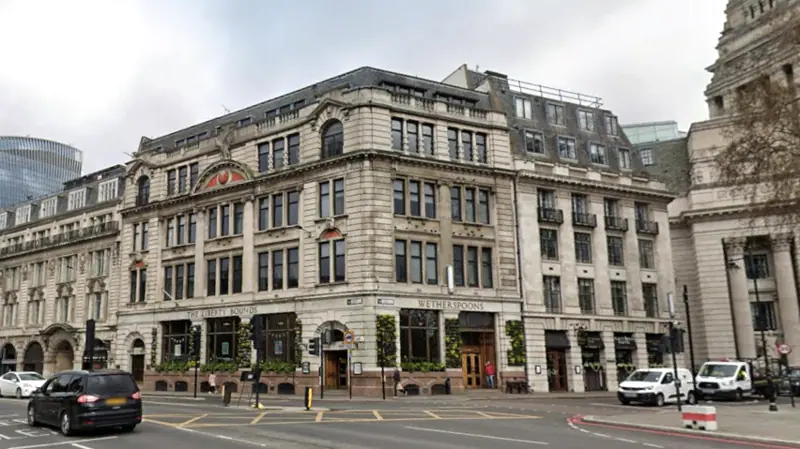 The exterior of a pub with large windows and flowers growing on the walls