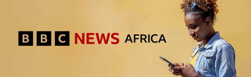 To the right of the banner a woman with sunglasses on her head and wearing a denim jacket and yellow T-shirt looks down at her mobile phone. A graphic for BBC News Africa in black and red is on the…