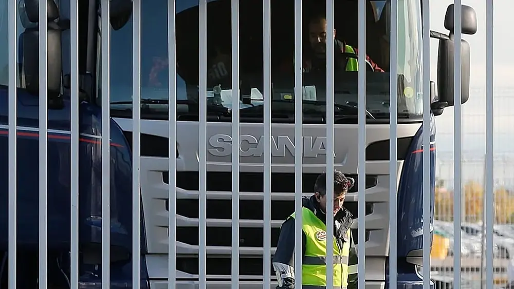 A security guard stands next to a truck behind a gate outside Amazon's main logistics centre in Madrid, Spain, on November 22, 2018.