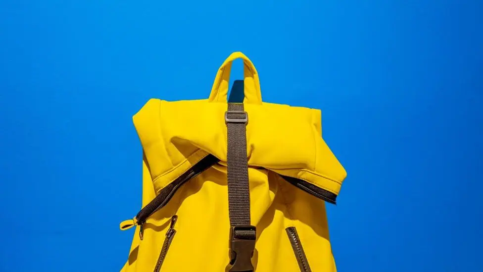 A yellow backpack with a bright blue sky beyond