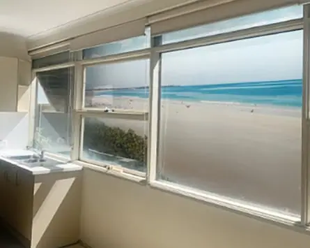 A photo from inside the unit of an apartment showing a mural of a beach out the window
