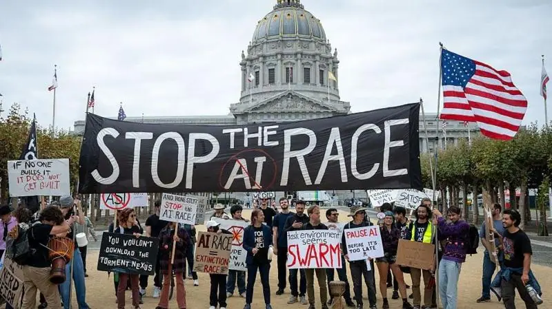 Protesters at an AI demonstration outside City Hall in San Francisco, California. Some in the crowd are holding a large black "Stop the AI race" banner, while others hold placards calling for a pause…