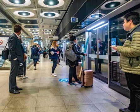 People standing on an underground platform some with roller suitcases