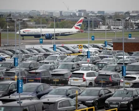 A full car park at Heathrow with a British Airways plane in the distance