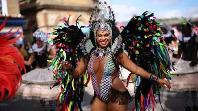 Woman in colourful outfit with colourful feathers dances