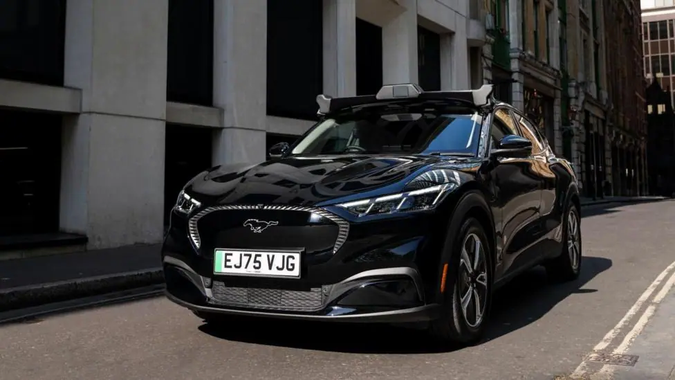 A black, hatchback car with a camera visible on its roof