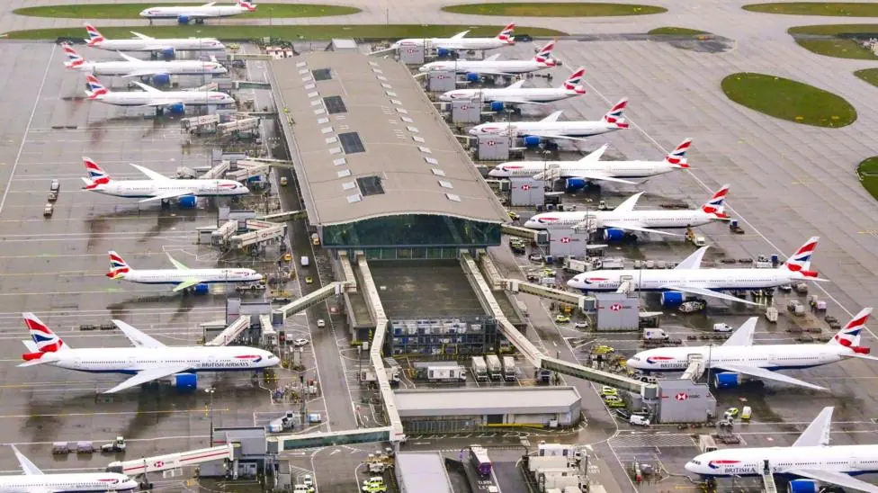 Multiple British Airways passenger aircraft parked at terminal gates on the tarmac at Heathrow Airport.
