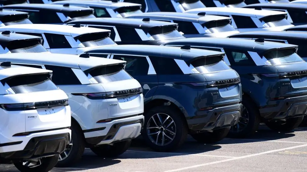 A photo taken in Halewood in 2025 shows rows of Range Rovers on the tarmac at a JLR factory outside on a sunny day.