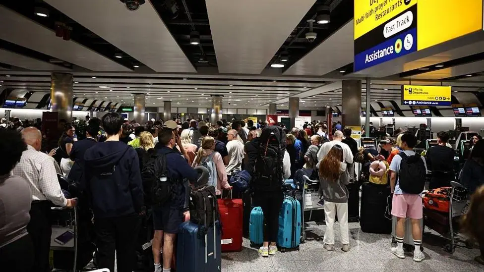 Delayed passengers wait and queue with their luggage at Terminal 3 of London Heathrow airport.