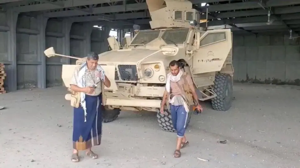 Screengrab of a video from Houthi-run Al Masirah TV showing an armed man walks next to an armoured vehicle in Mocha, Yemen, after the Houthis reportedly seized the Red Sea port city (10 September…