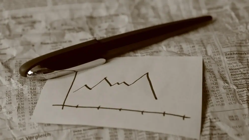 pen rests on paper showing sketched graph going lower.
