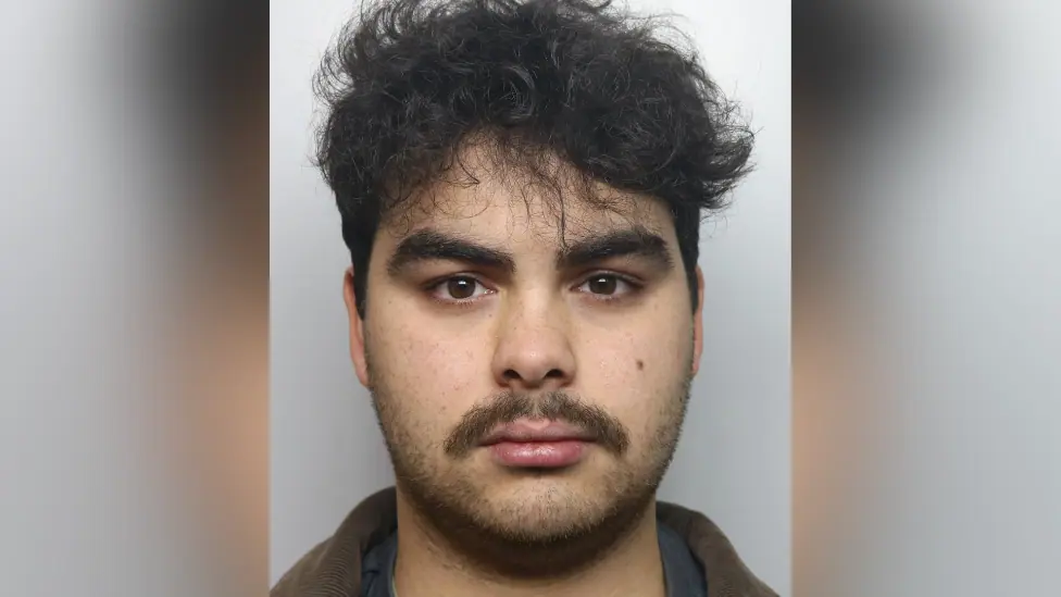 Kyran Smith mugshot. He has dark hair and dark stubble.