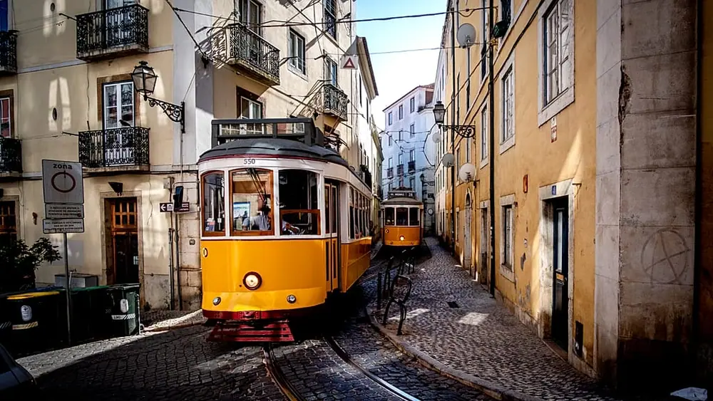 Trams make their way through the narrow streets of the Alfama district in Lisbon, Portugal,