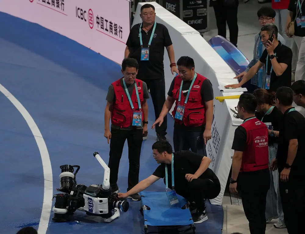 FILE. A technician checks a robot after a fall at the end of the 1,500-meter race during the World Humanoid Robot Games in Beijing, China, 23 Aug. 2026