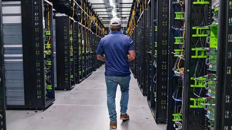 A man walking isnide a data centre, with rows of servers.