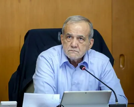 Pezeshkian sits as a desk behind a microphone.