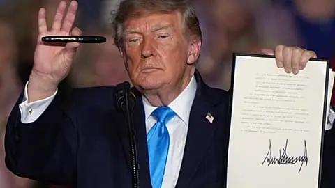 FILE. US President Donald Trump holds up a pen and a signed executive order at a campaign rally at the Pinnacle Bank Expo Center, Grand Island, Nebraska, 5 Oct. 2026