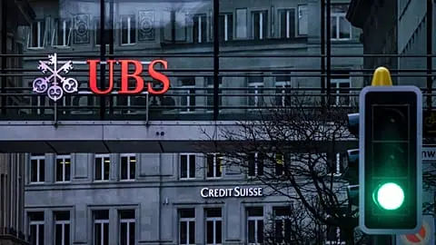 FILE. A traffic light signals green in front of the logos of the Swiss banks Credit Suisse and UBS in Zurich, Switzerland, 19 March 2023