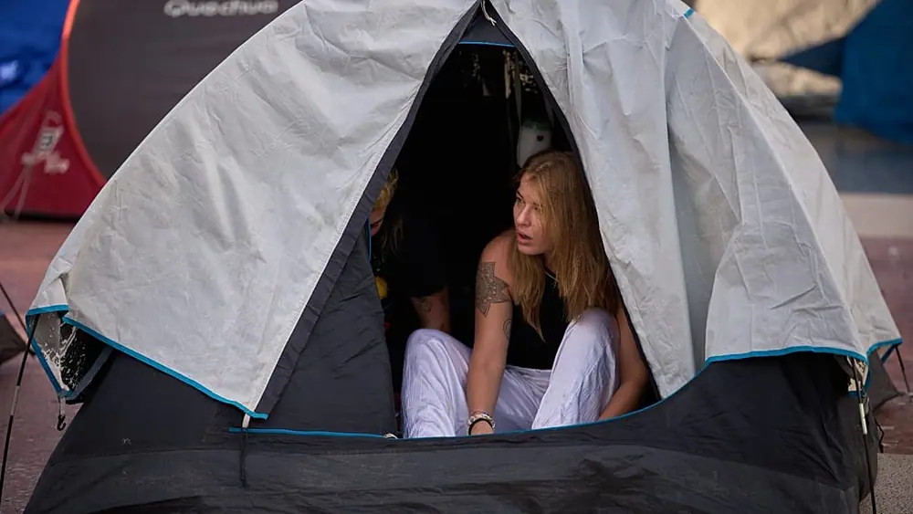 Woman wakes after camping overnight at Barcelona rent protest, Sept. 30, 2026.