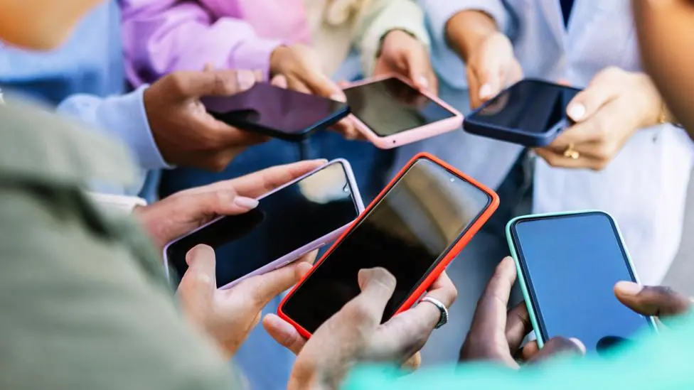 A group of young people holing their smartphones.