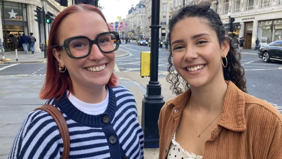 Katie Burrows, 23 (left) and Yasmin Trimble, 22, (right) smile at the camera in central London