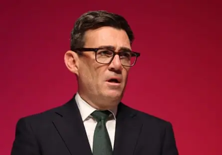 Andy Burnham in a suit with a red background