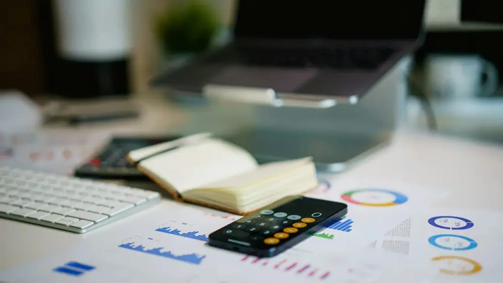 Laptop, calculator and documents on table (Jakub Żerdzicki/UJnsplash)